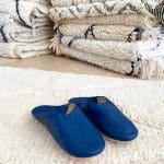 Moroccan handmade slippers in blue on top of beni ouarain rug
