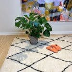 Marokkanske håndlavede slippers i orange oven på beni ouarain tæppe med plante ved siden af