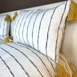 Witte Marokkaanse handgeweven sprei met zwarte strepen en gele pompons, met bijpassende kussens