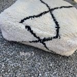 Quadratisches marokkanisches, handgenähtes Bodenkissen aus Wolle mit einem großen schwarzen Kreuzmotiv von der Seite