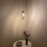 Marokkansk håndlaget, svingende, dråpeformet lampe som henger over et dekorasjonsbord, tent i mørket