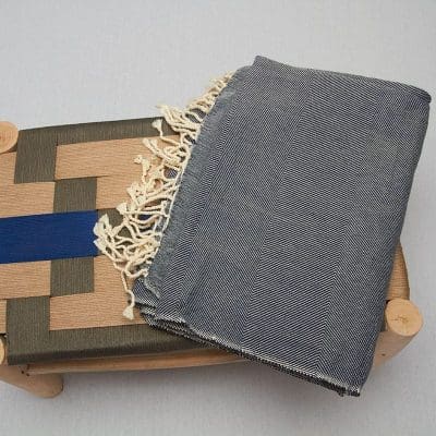 Marokkansk håndvævet sengetæppe i blå, på en bænk