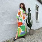 Model in Marokkaanse handgeweven jurk met veelkleurig fruitpatroon naast cactus