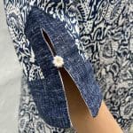 Model in Marokkaanse handgeweven denimjurk met bladpatroon, dicht bij de armen