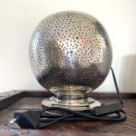 Marokkansk bordlampe i sølvmetall med enkelt hullmønster, slått av på en hylle