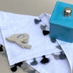 Petite serviette blanche tissée main avec pompons gris et noirs, avec décorations latérales, fermer