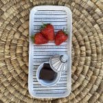 Kleine Tajine-Schale mit Punktmuster und Schokolade darin, auf einem Teller mit passendem Muster und Erdbeeren darauf