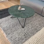 Moroccan handwoven carpet in shades of gray and beige with wool details, lying under a coffee table in a living room