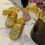 Marokkanische handgefertigte Hausschuhe in Moutarde-Gelb mit Pailletten auf einem Beni Ouarain-Teppich mit seitlichen Puffs, nah