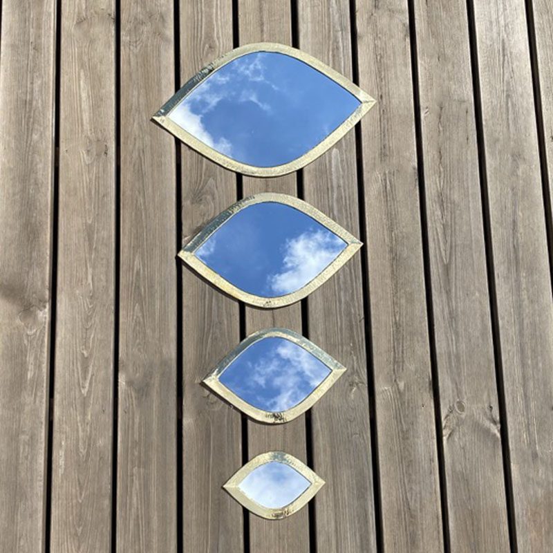 Tibladin Marokkanske Spejle Guld Med Banket Kant 1.jpg Four Moroccan handmade eyelid-shaped mirrors with gold trim, in four different sizes, lying next to each other