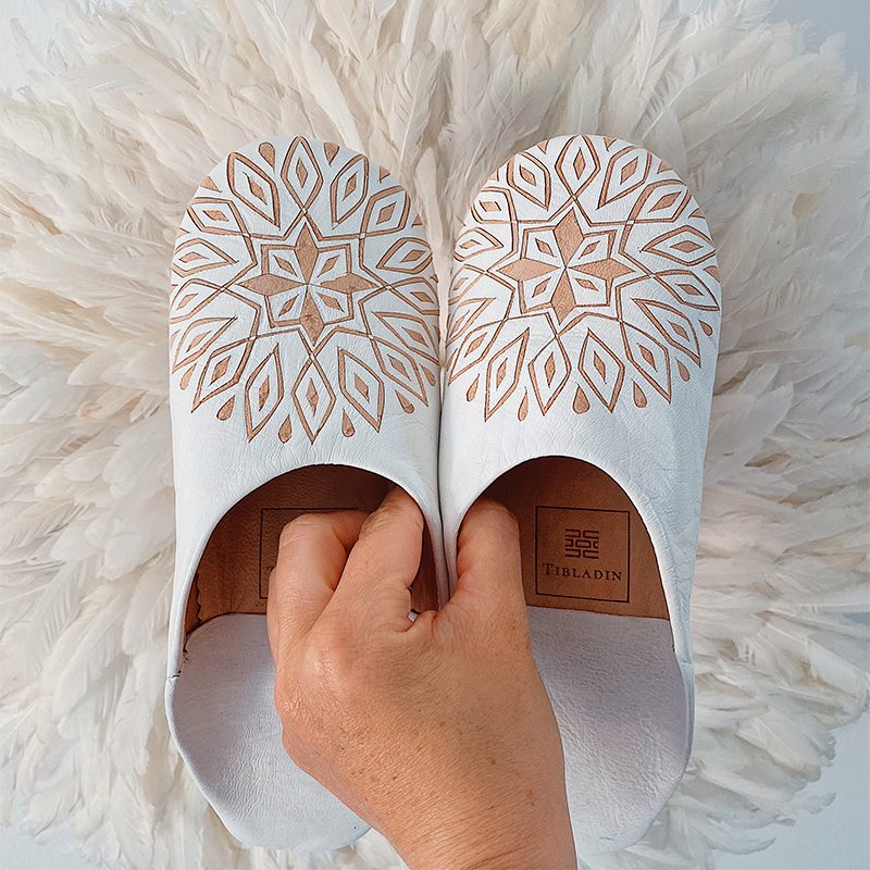 Tibladin Slippers Hvid Med Moenster LS 1.jpg Model der holder Marokkanske håndlavede slippers i hvid med mønster