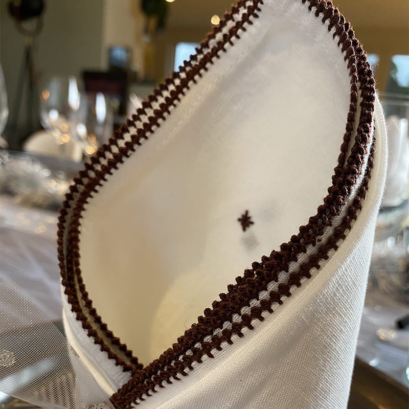 Tibladin Stofserviet Bruntbroderi 20100009 LS3 1.jpg Marokkansk håndbroderet stofserviet med brun kant, foldet pænt, tæt
