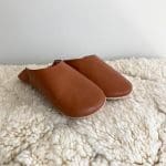 Moroccan handmade slippers in light brown on top of beni ouarain rug