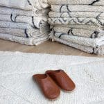 Moroccan handmade slippers in light brown on top of beni ouarain rug