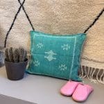Green cactus silk pillowcase with bluish undertones. Turquoise hue. White stitching/patterns.