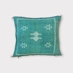 Green cactus silk pillowcase with bluish undertones. Turquoise hue. White stitching/patterns.