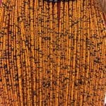 Collier composé de perles orange chaud et noires et d'un anneau de cou orange en cuir tressé.