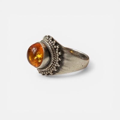 Honingring, met een ronde, gladde steen in het midden in bruin/gouden tinten, omringd door zilveren details.