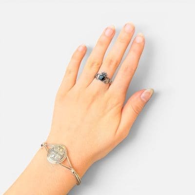 Unik ring som viser to hender som holder et svart hjerte med en krone på.