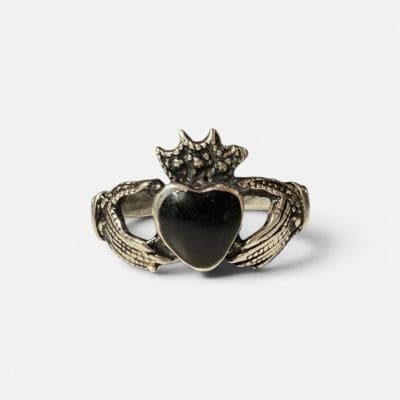 Unik ring som viser to hender som holder et svart hjerte med en krone på.